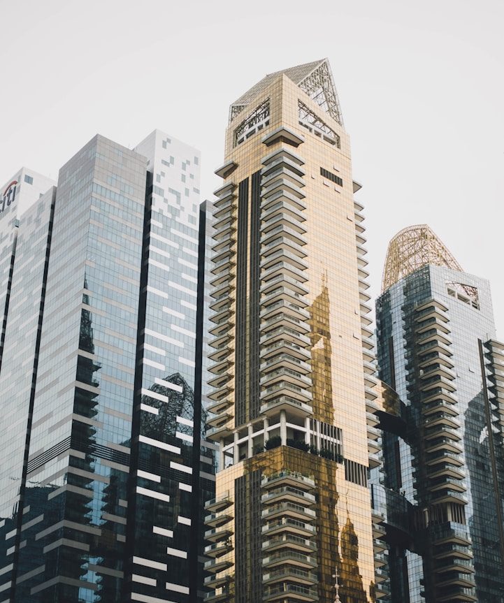 invertir en bienes y raíces Rascacielos modernos con fachadas de vidrio y detalles dorados.